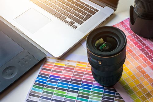 Kameran objektiivi väripalettien päällä työpöydällä